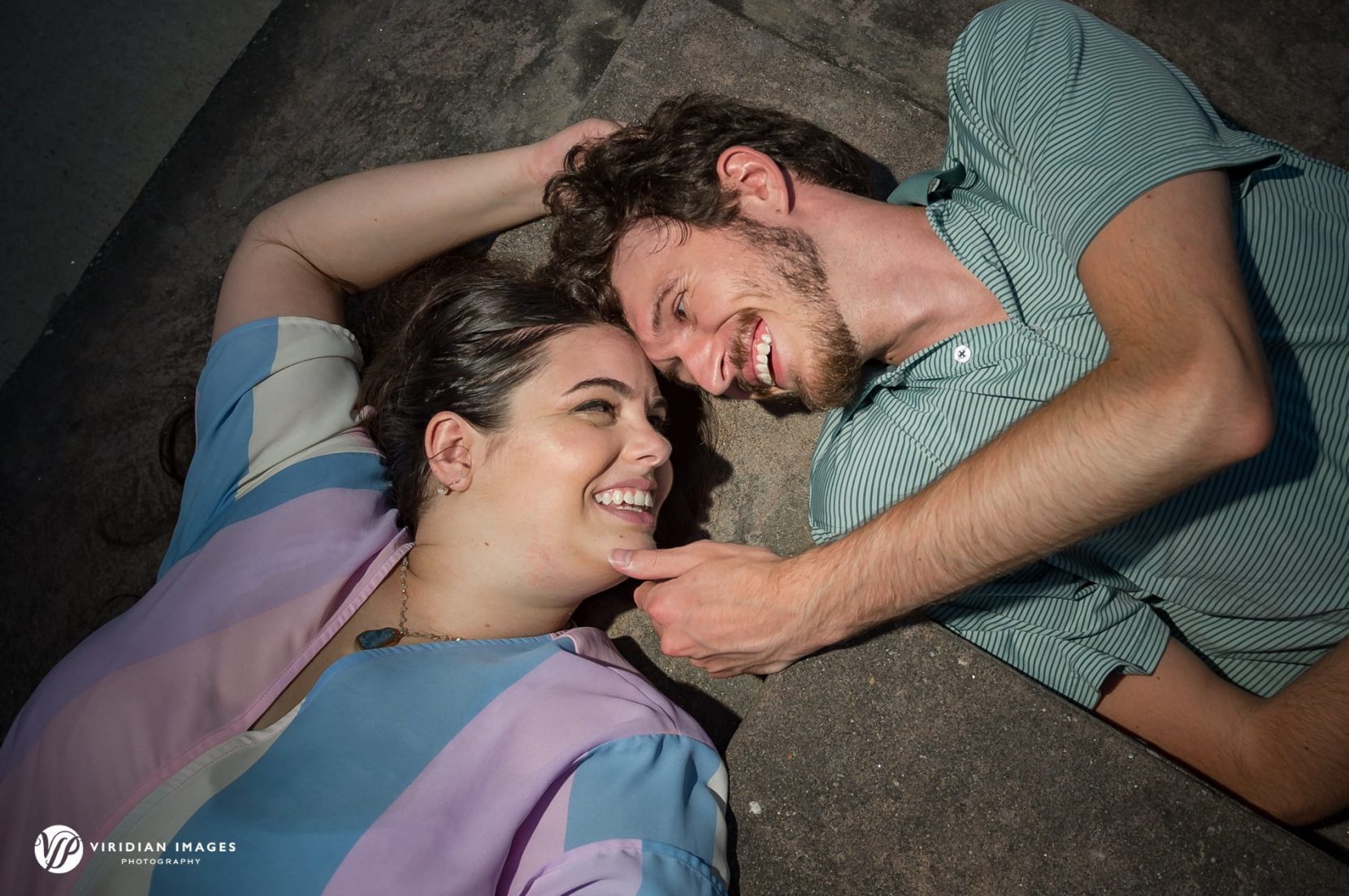 Cillian and Calen lying on floor seeing each other during engagement session at UGA north campus