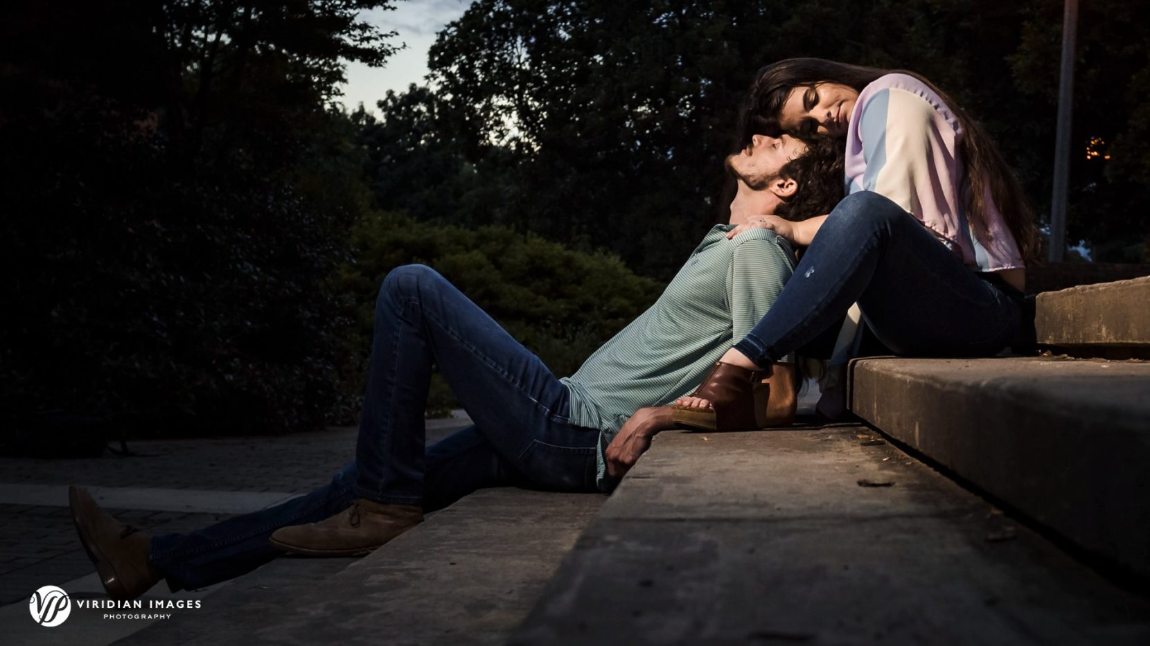 Engaged couple sitting on concrete stairs at dusk at UGA north campus