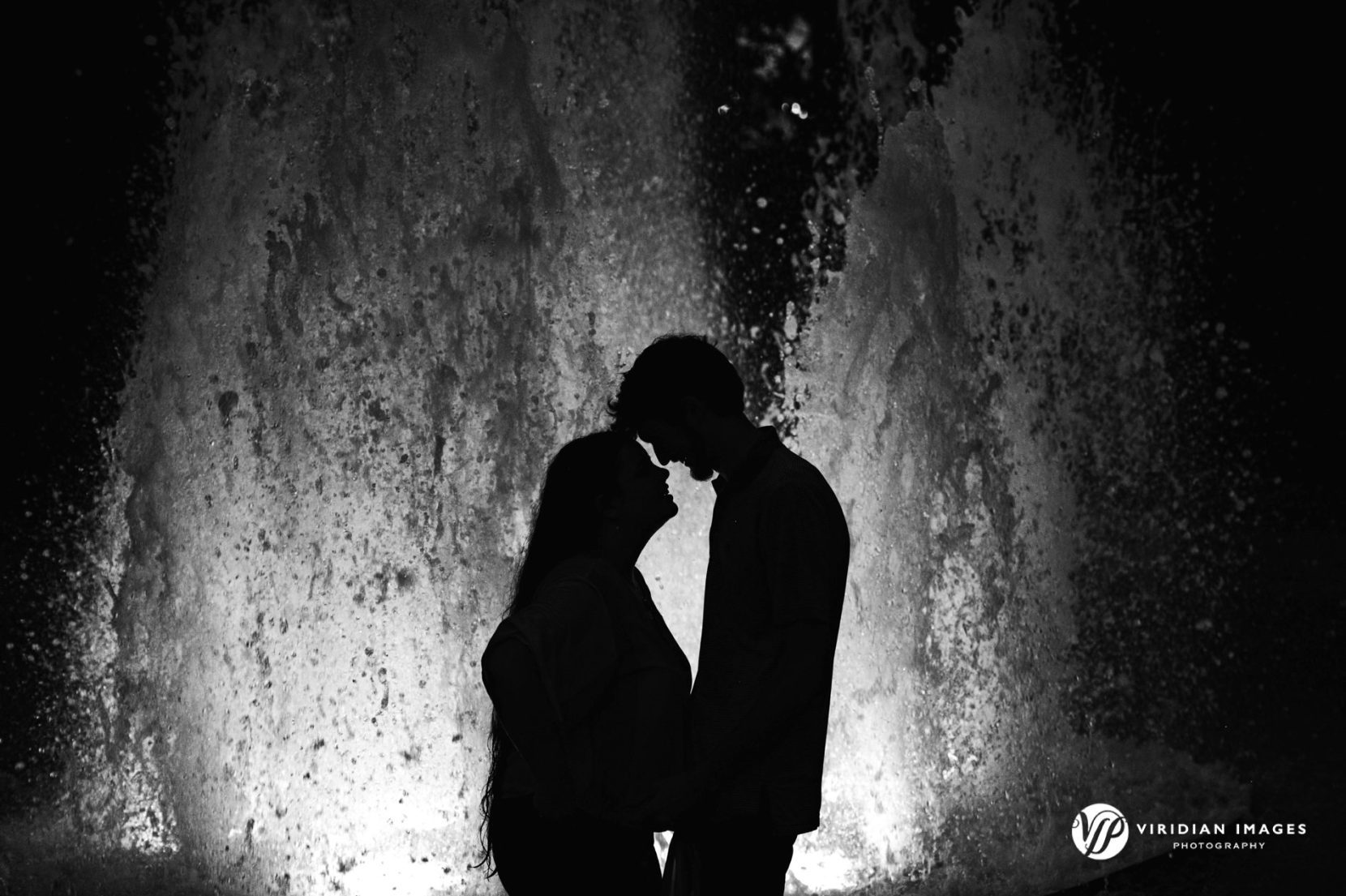Silhouette of couple against lit water fountain at UGA north campus