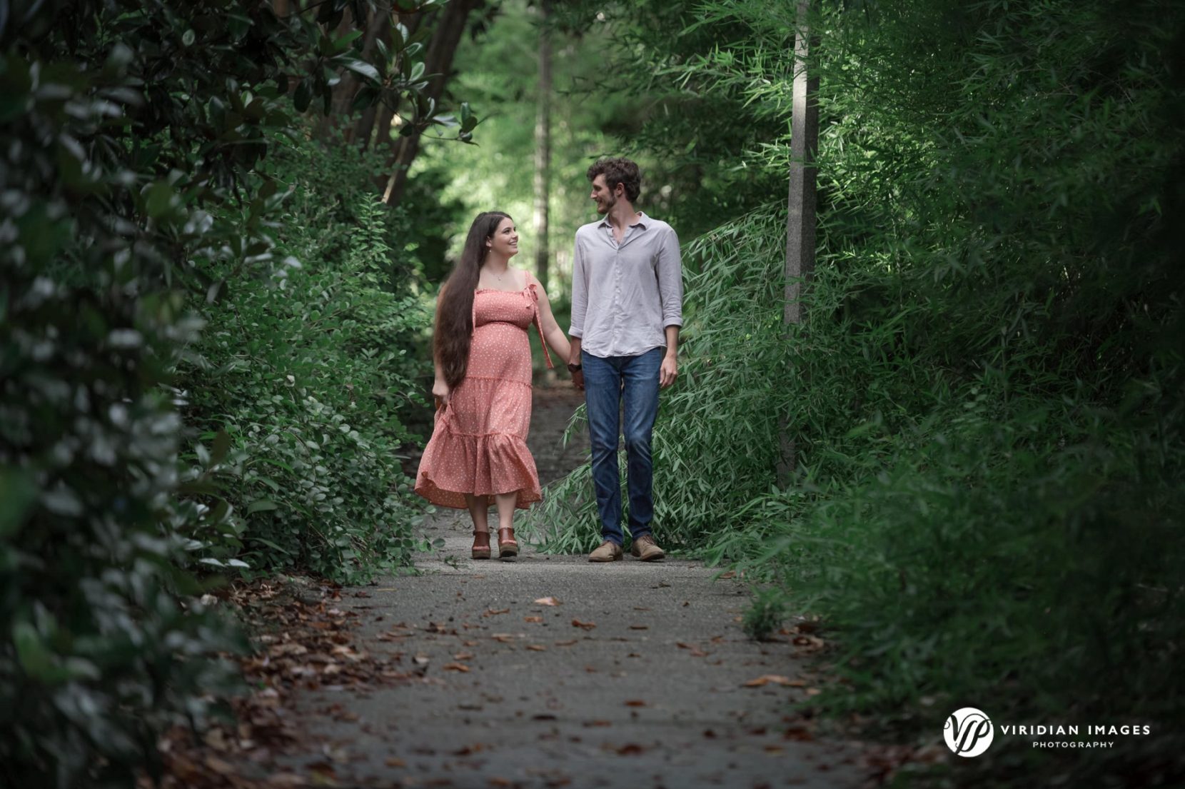 Engaged couple walking hand-in-hand along pathway at UGA North Campus in Athens, GA.