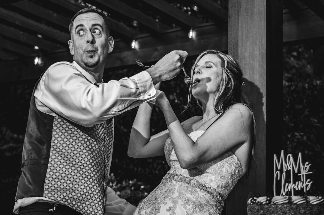 Groom distracted while feeding bride cake during cake cutting at wedding reception.