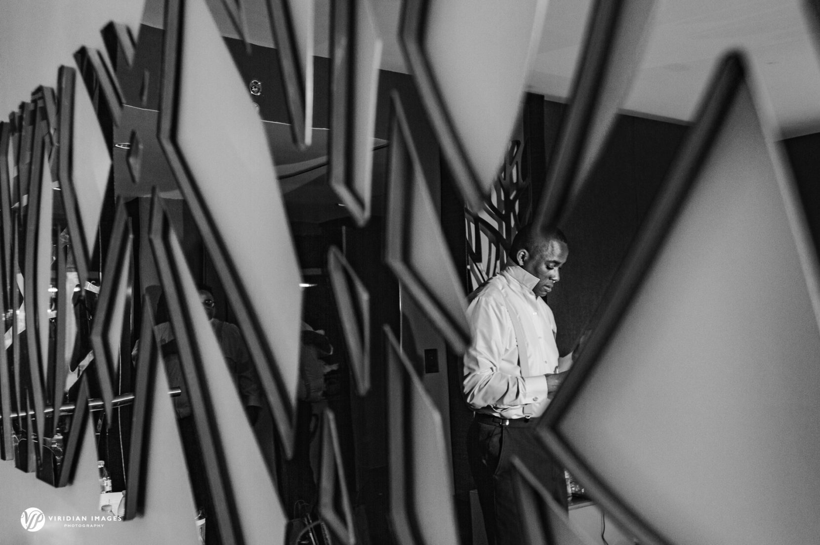 reflection of groom through reflective wall art at W Hotel Atlanta