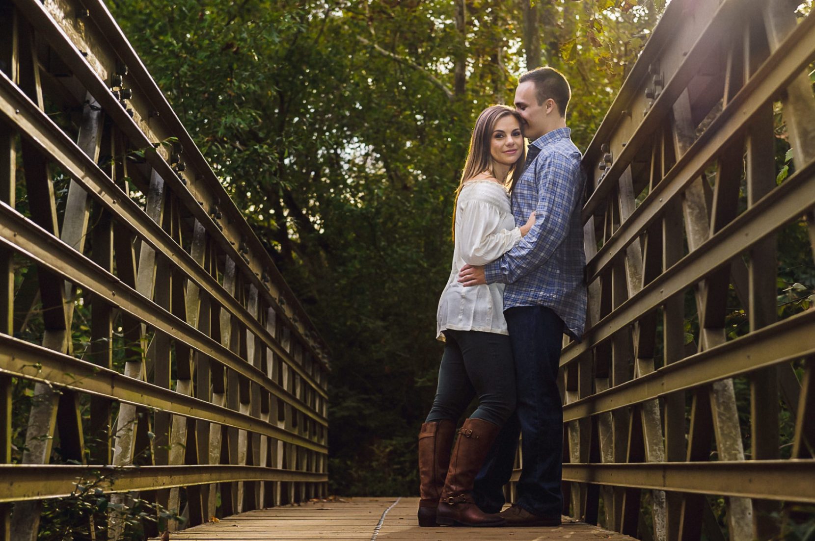 Couple leaning against metal bridge during fall engagement session at East Palisades Trail.