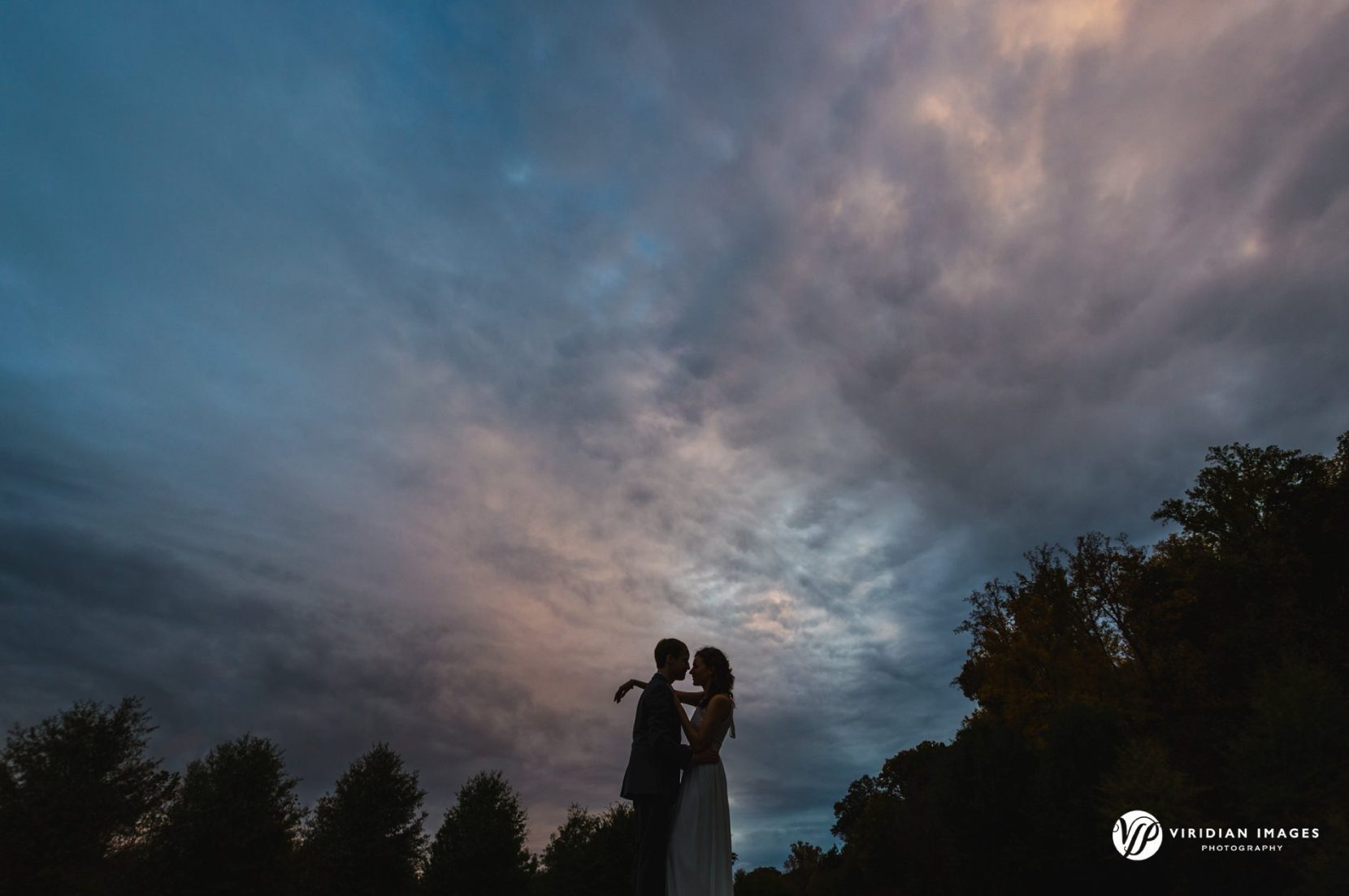 engaged couple silhouette against moody golden hour skies