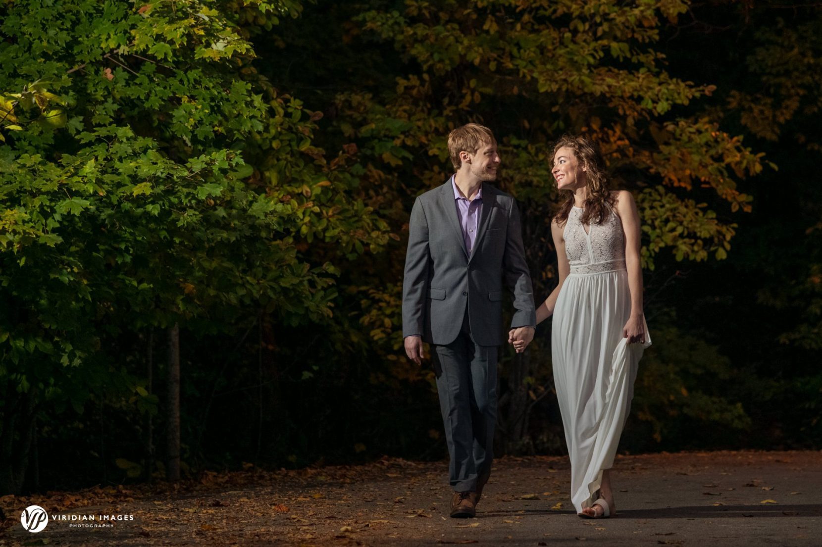 Romantic portrait of the couple framed by trees and soft evening light.