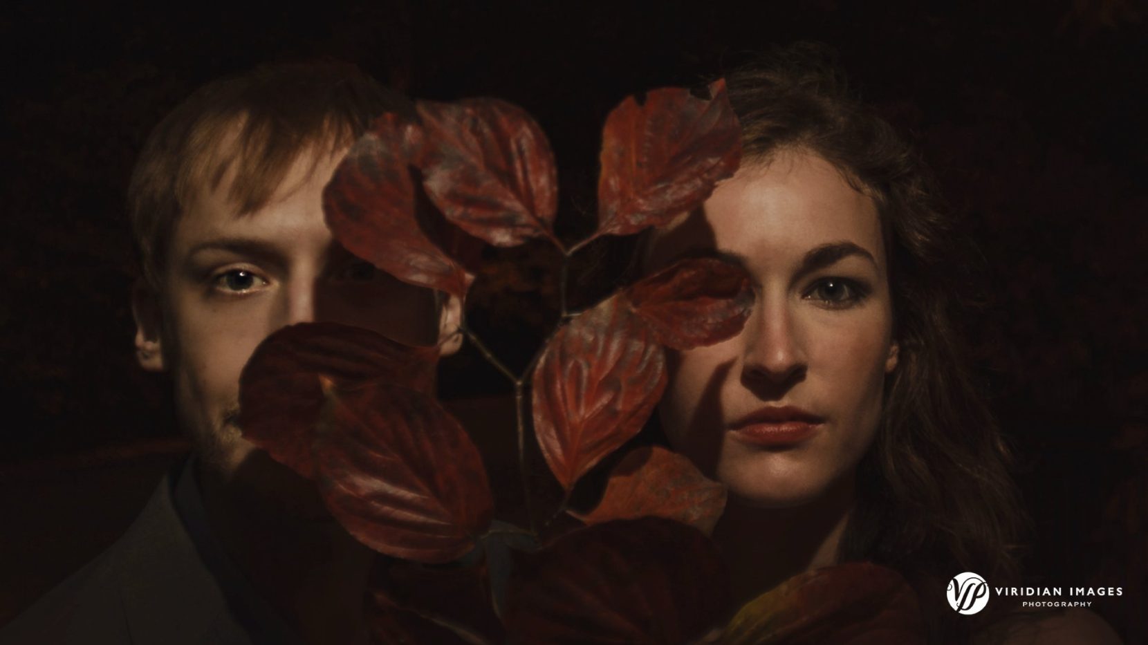 Artsy and creative close-up photo of couple between large burgundy fall leaves at Piedmont Park