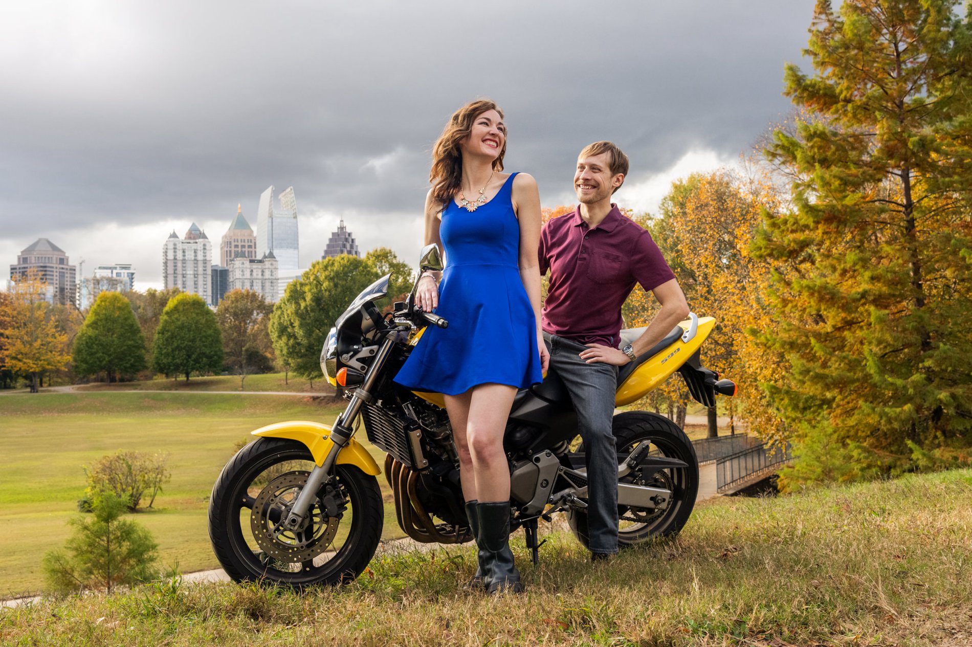 Creative low-angle portrait of Jenny and James with their motorcycles against cloudy fall skies