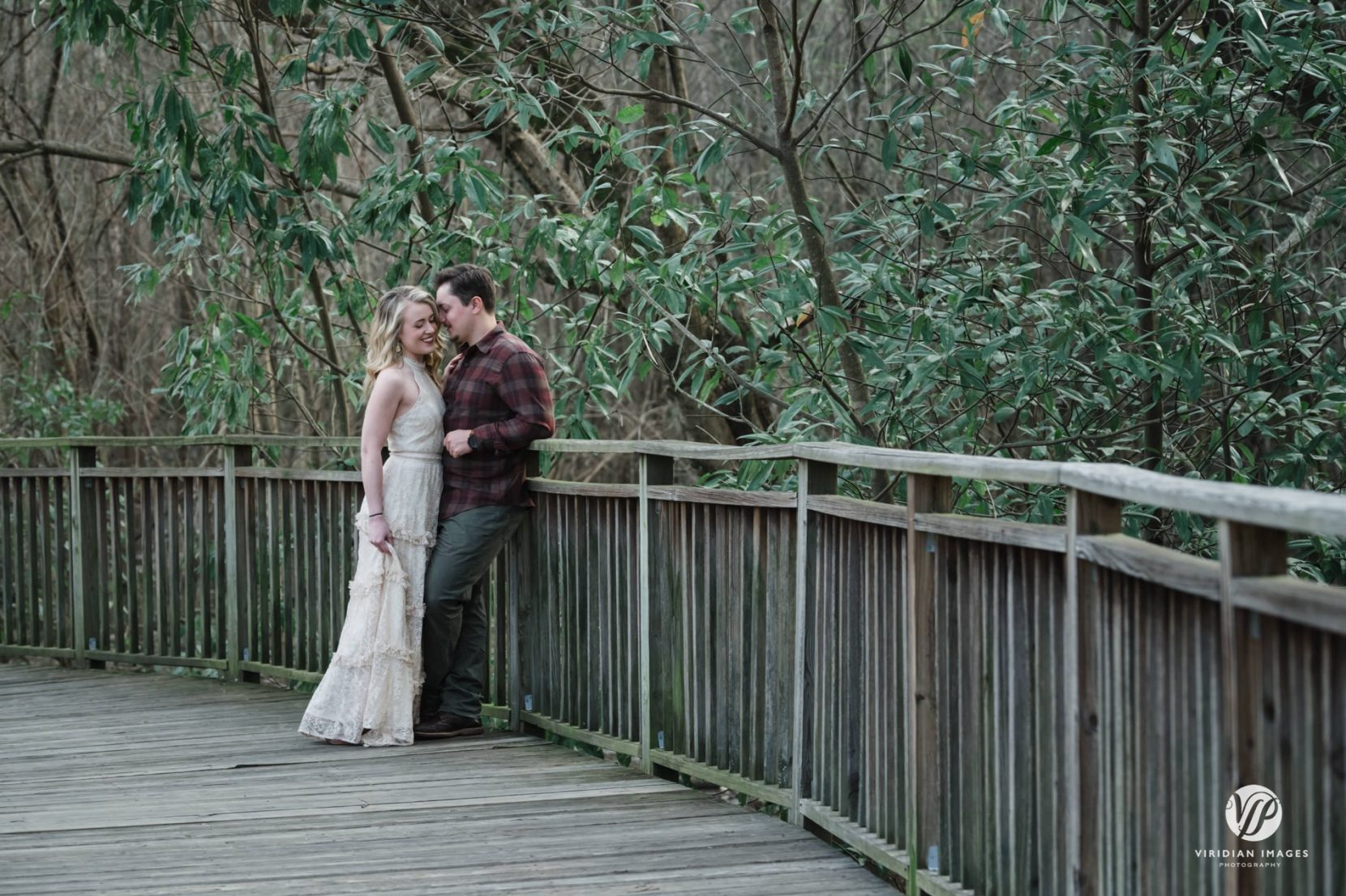 Winter engagement session at Piedmont Park leaning against railing on boardwalk