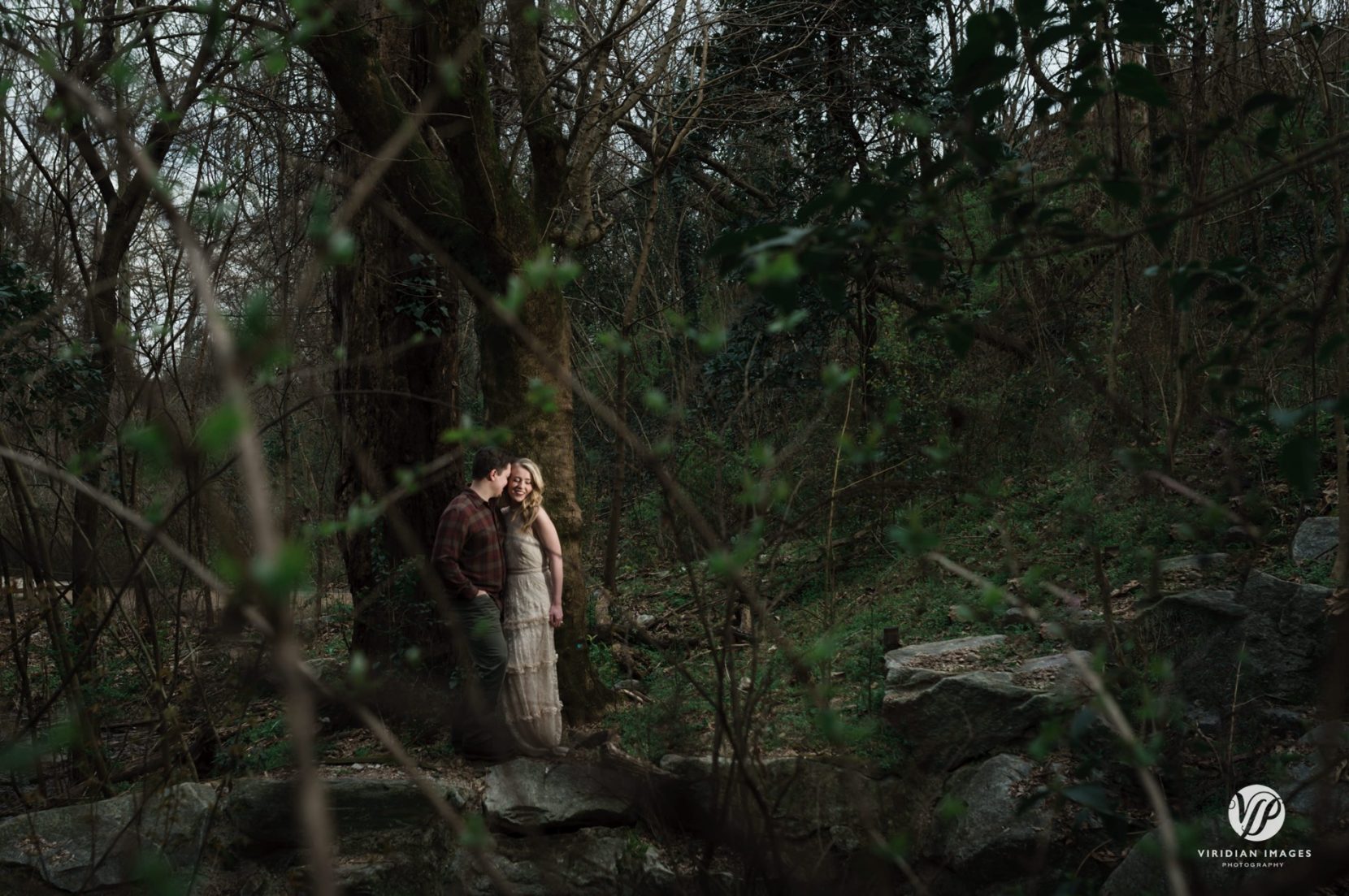 couple standing among bare trees during engagement session in Piedmont Park