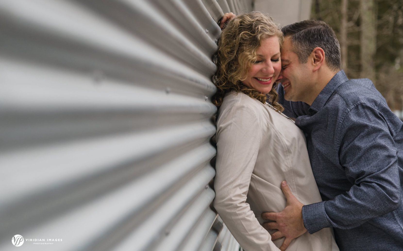 Romantic couple embrace against metal corrugated wall at Sweetwater Creek Park