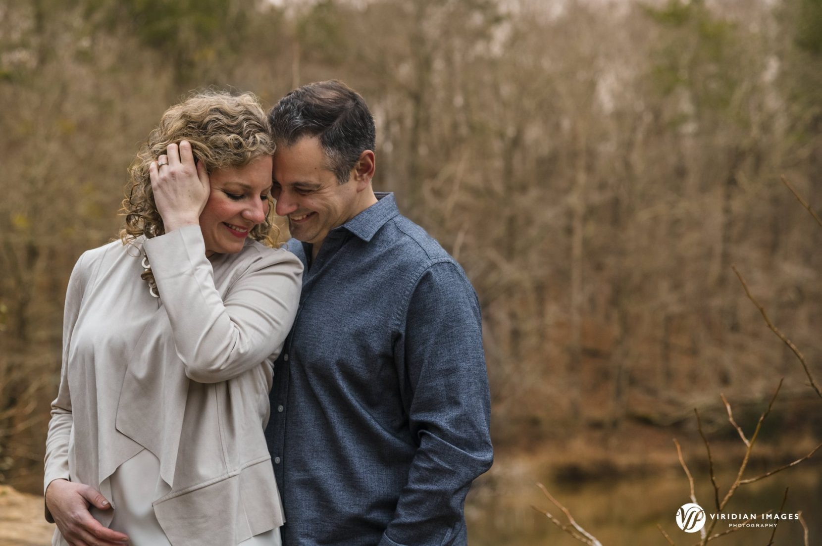 Couple snuggling during winter engagement session at Sweetwater Creek Park in Atlanta