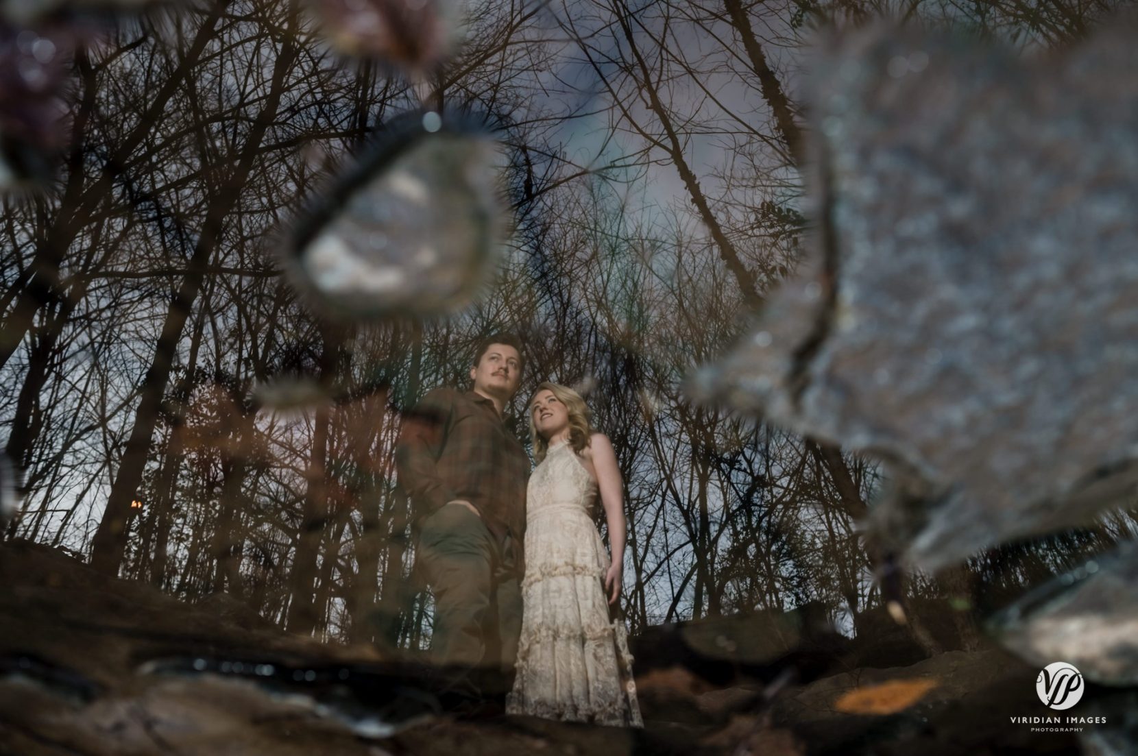 Reflection of engaged couple against bare trees and sky at Piedmont Park