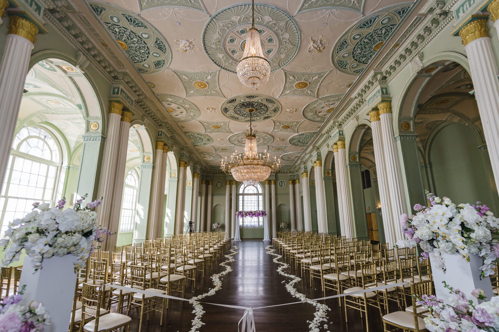 Empty ceremony setup at Biltmore Ballrooms with gold chairs and floral aisle