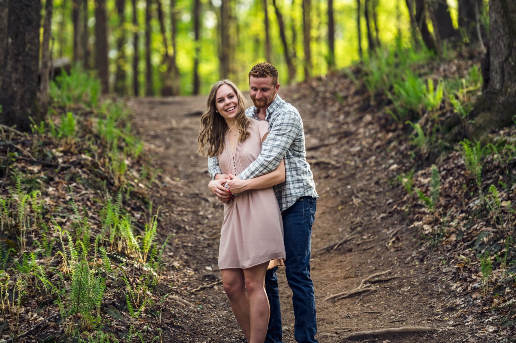 Playful couple stop along trail during engagement session