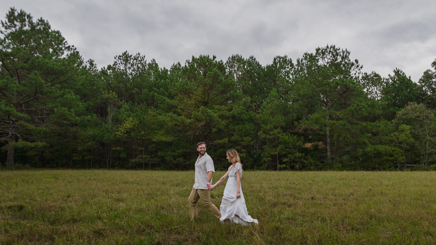 Couple walking through field during engagement session at Birmingham Park, Milton, Georgia.