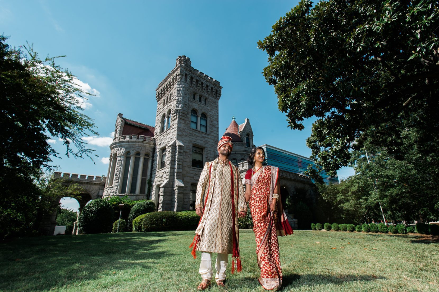 Couple walking together in front of large historic estate architecture with formal structure