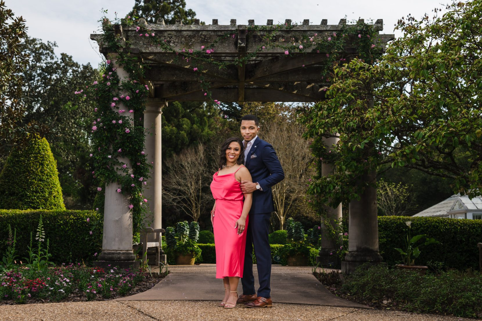 Couple standing in a structured garden with formal landscaping and architectural elements