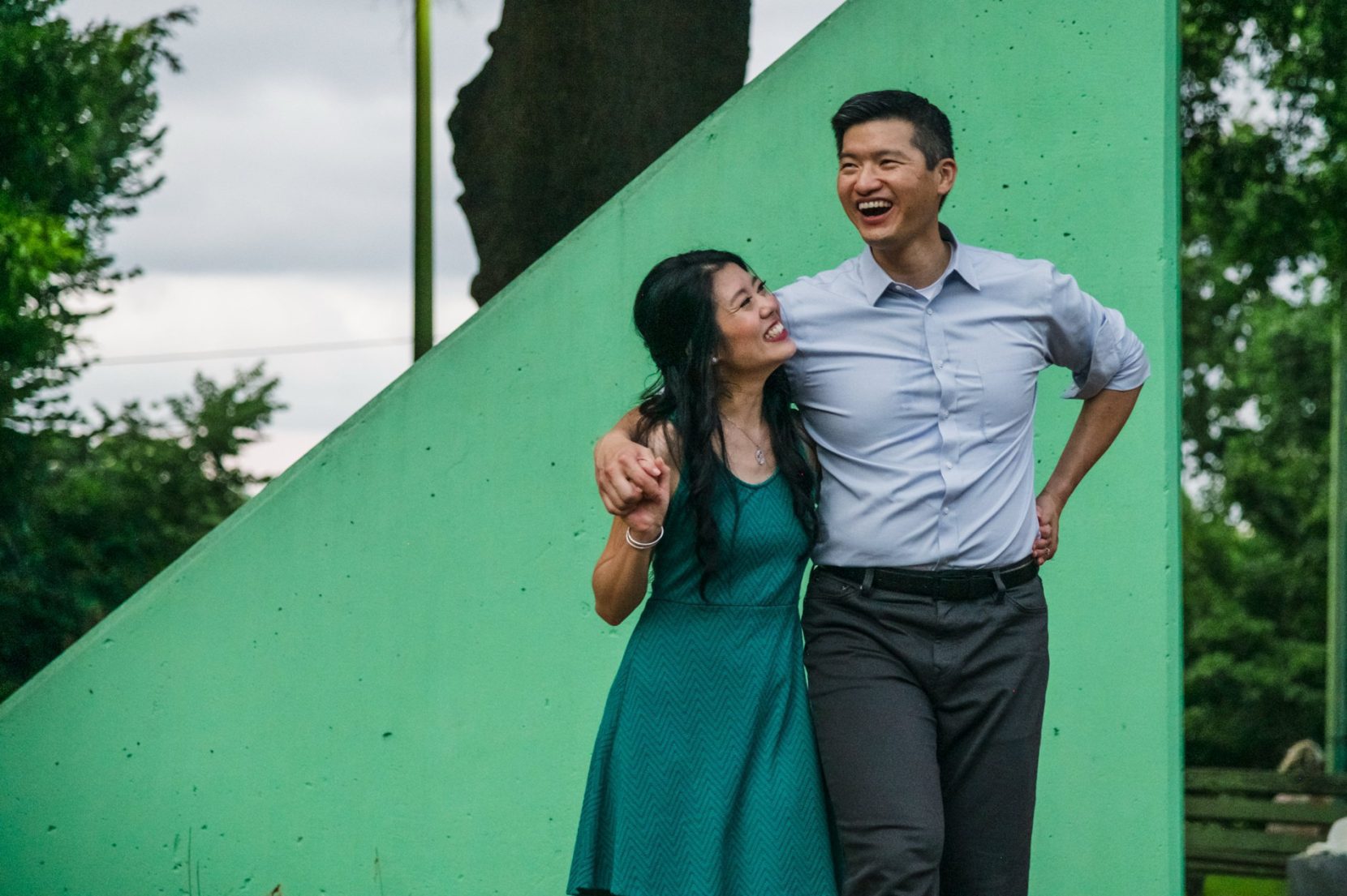 Happy couple walking through playground in Atlanta park during engagement session