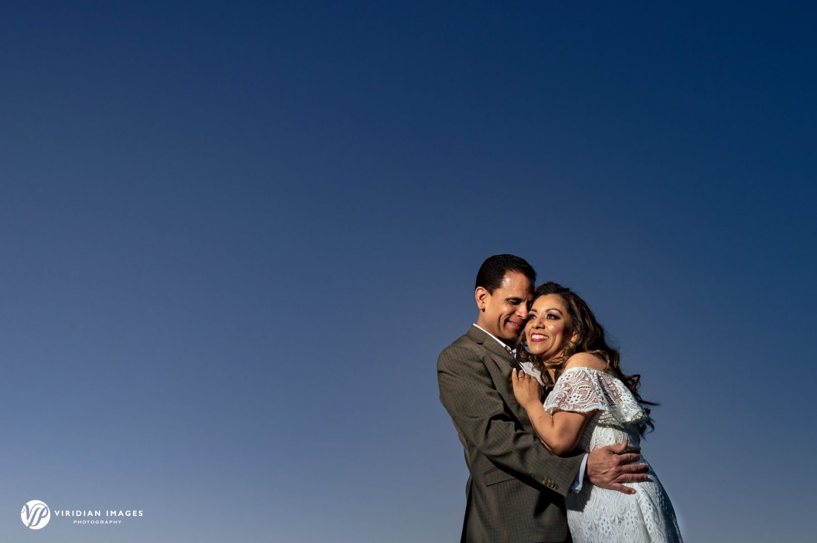 Couple embrace under dark blue skies during urban engagement session in Atlanta
