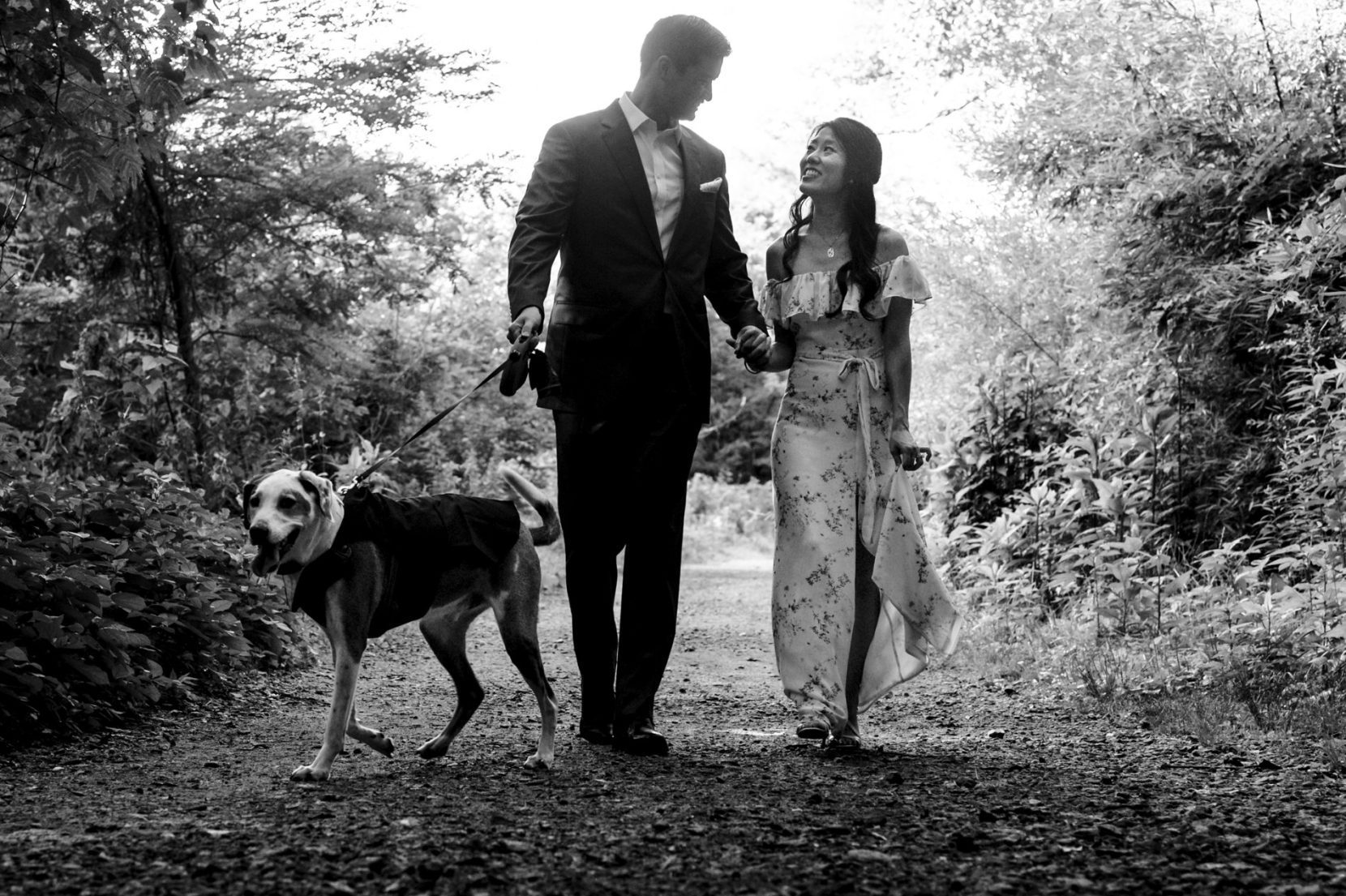 Black and white photo of couple during their engagement session with their dog at the park