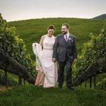 bride and groom walking between grape vines at golden hour